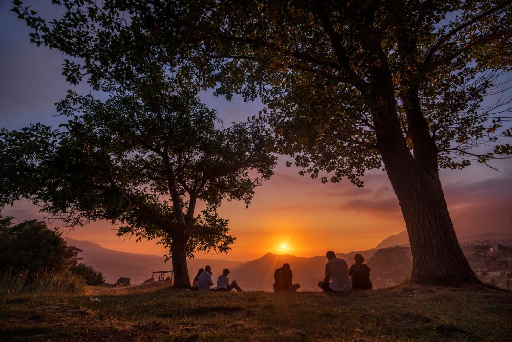 People sit and reflect as the sun sets over the scenic Kadisha Valley, a holy landmark for Lebanon's Maronite Christians, in the northeast mountain town of Bcharre, Lebanon, Friday, July 21, 2023.