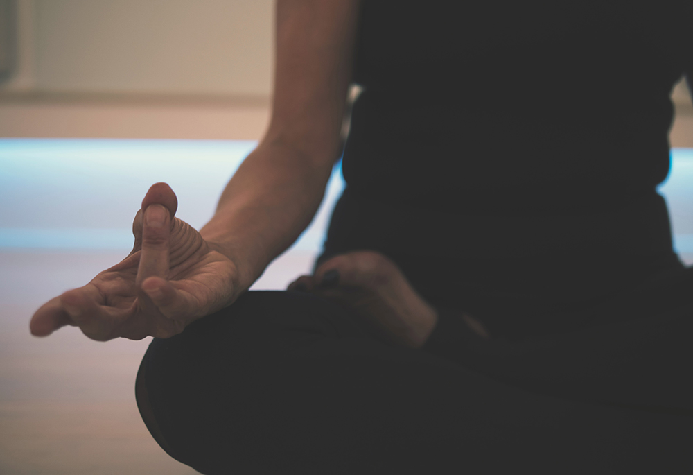 Closeup of a person meditating in a seated position (Unsplash/JD Mason)