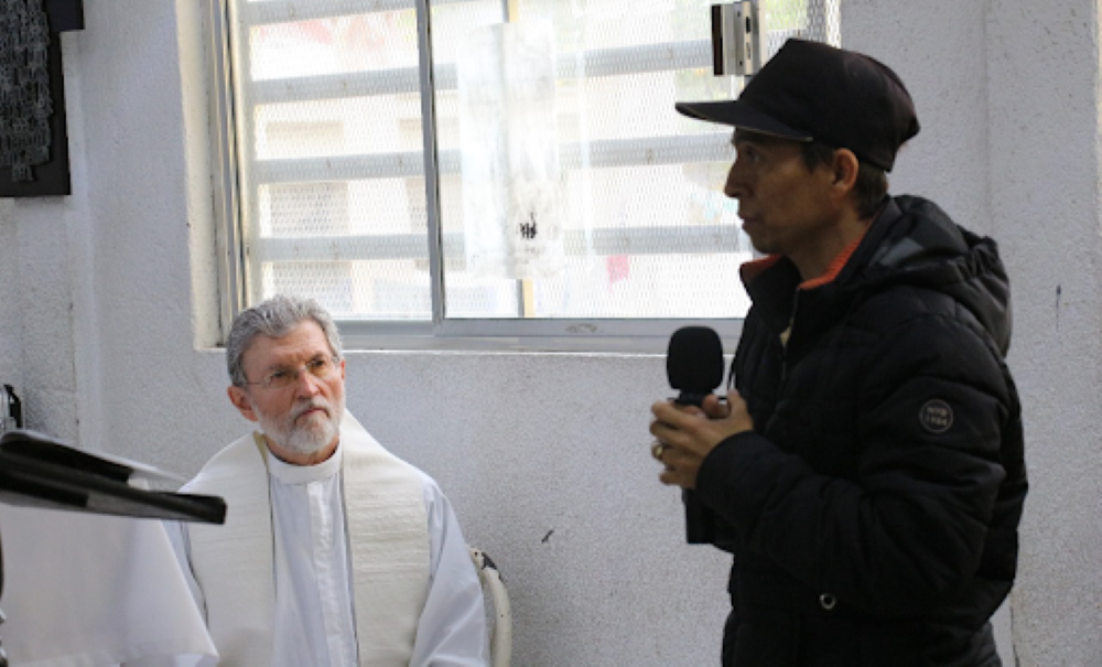 Msgr. Luis Eduardo Villarreal listens during Epiphany Mass at Casanicolás on Jan. 7 as Carlos describes traveling through the Darien jungle between Colombia and Panama and traveling on the Mexican freight train known as "the beast" or "train of death."