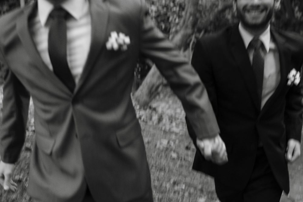 Two men wearing suits and holding hands
