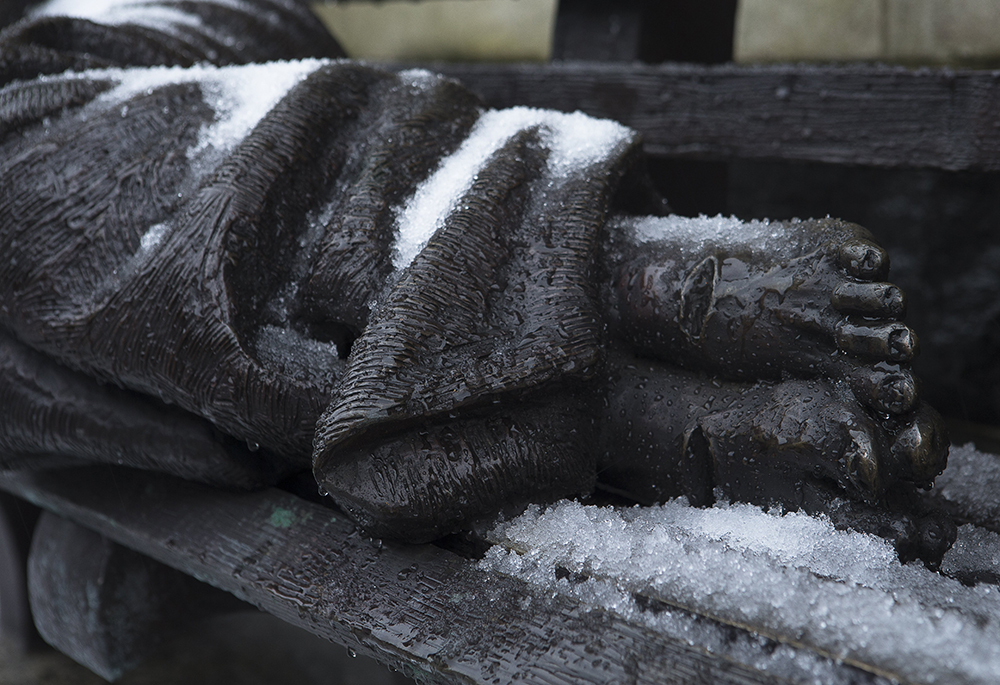The "Homeless Jesus" sculpture by Timothy Schmalz is seen covered with snow outside Catholic Charities of the Washington Archdiocese Dec. 16, 2020. (CNS/Tyler Orsburn)
