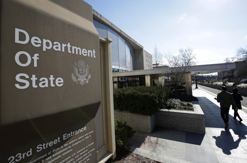A sign saying "Department of State" is visible outside of a brown-gray building
