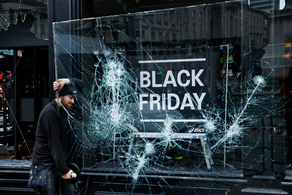 A man works to remove a broken window from a sport shop in Dublin Nov. 24, 2023, which was damaged in a night of rioting that followed a school stabbing attack Nov. 23. (OSV News photo/Clodagh Kilcoyne, Reuters)