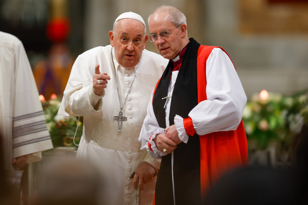 Pope Francis leans towards Archbishop Welby while speaking and pointing