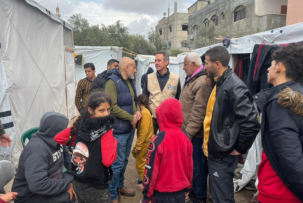 Sean Callahan, president of Caritas North America and CEO of Catholic Relief Services, in a tan vest, is pictured at a camp for displaced people during his visit to southern Gaza Jan. 23, 2024. (OSV News/Courtesy Catholic Relief Services)