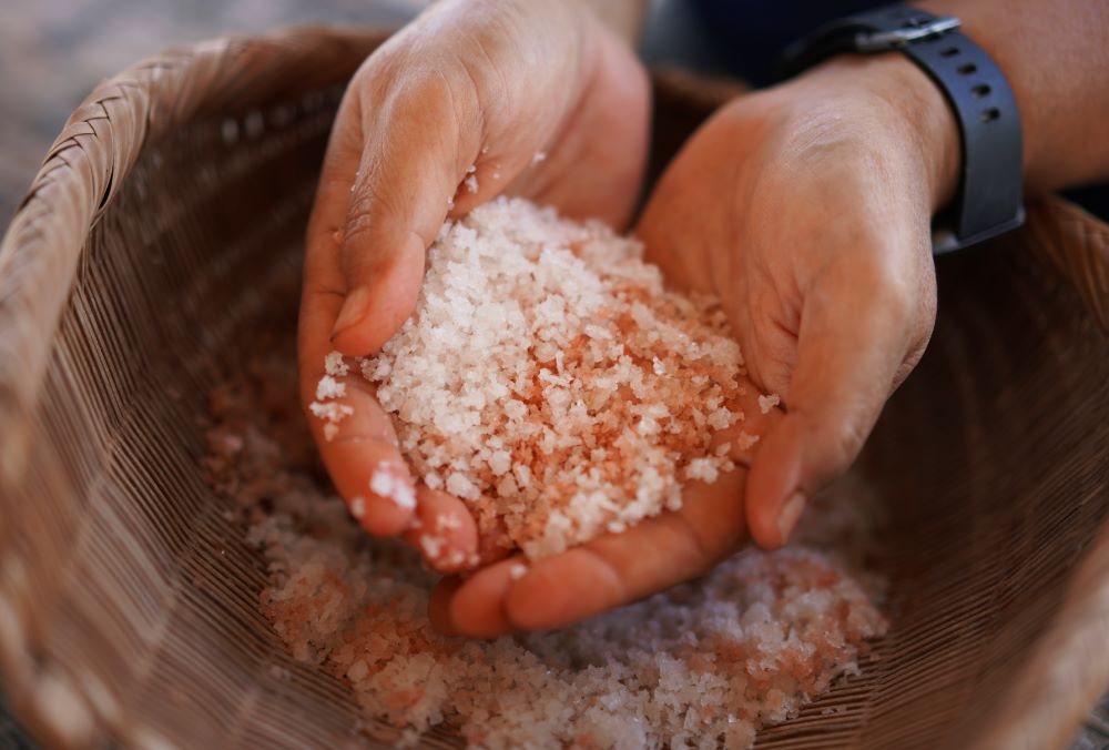 Malia Nobrega-Olivera, a Native Hawaiian salt maker, holds Hawaiian salt, or "paakai," on Monday, July 10, 2023, in Hanapepe, Hawaii. An important part of this cultural and spiritual practice is that this salt can only be traded or given away, not sold. (AP Photo/Jessie Wardarski)