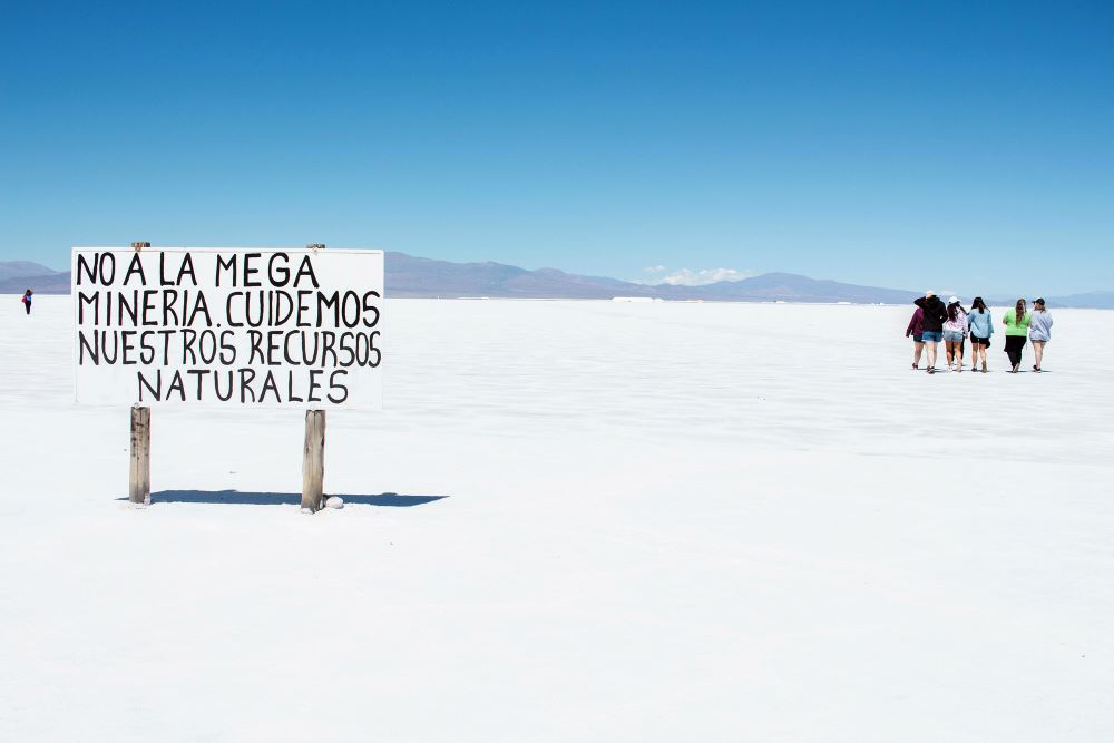 Tourists visit Salinas Grandes salt flats in Jujuy province, Argentina. A sign in Spanish reads “No to mega mining. Let’s take care of our natural resources.” (Photo by Maggy Idrobo López/Pexels/Creative Commons)