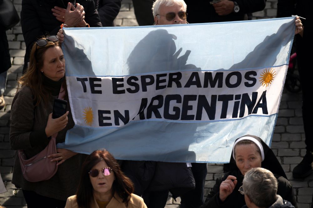A couple in St. Peter's Square at the Vatican holds up a sign on an Argentine flag saying, "We are waiting for you in Argentina," as Pope Francis leads the recitation of the Angelus prayer Jan. 14. 