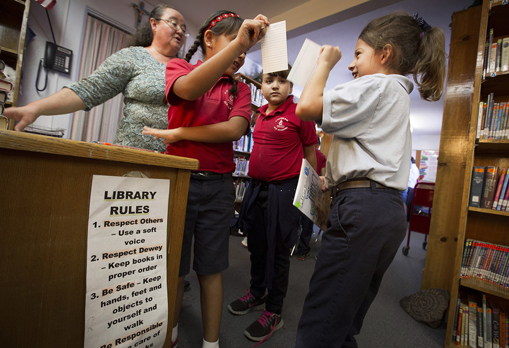 Students check out books in the library at Santa Cruz Catholic School, a Notre Dame ACE Academy in Tucson, Arizona, Oct. 22, 2014. Santa Cruz was on the verge of closing when the University of Notre Dame's Alliance for Catholic Education stepped in to boost enrollment and academics, help the schools achieve financial stability and bolster their Catholic mission. (CNS/Nancy Wiechec)