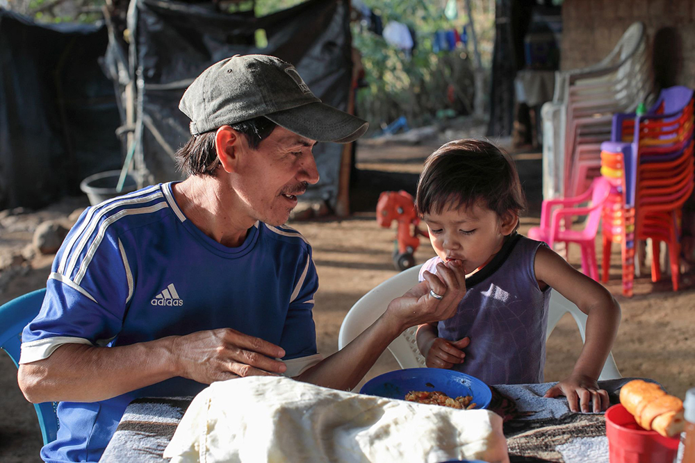 Farmer Santos Sorto feeds his son, Caleb, in La Caída, El Salvador. The family participates in a Catholic Relief Services program, which aims to mitigate the impact of COVID-19 pandemic and losses due to climate change. (OSV News/Silverlight/Catholic Relief Services/Oscar Leiva)