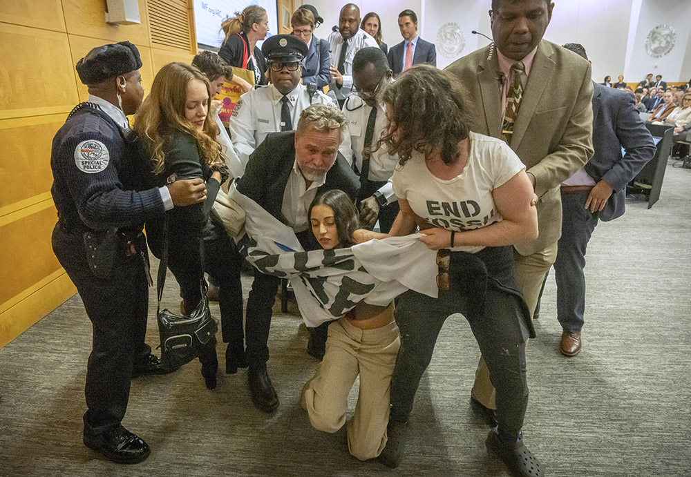 Climate protesters are removed after interrupting a speech by Federal Reserve Chairman Jerome Powell at the 24th Jacques Polak Research Conference at the International Monetary Fund on Nov. 9, 2023, in Washington, D.C. (AP/Mark Schiefelbein)