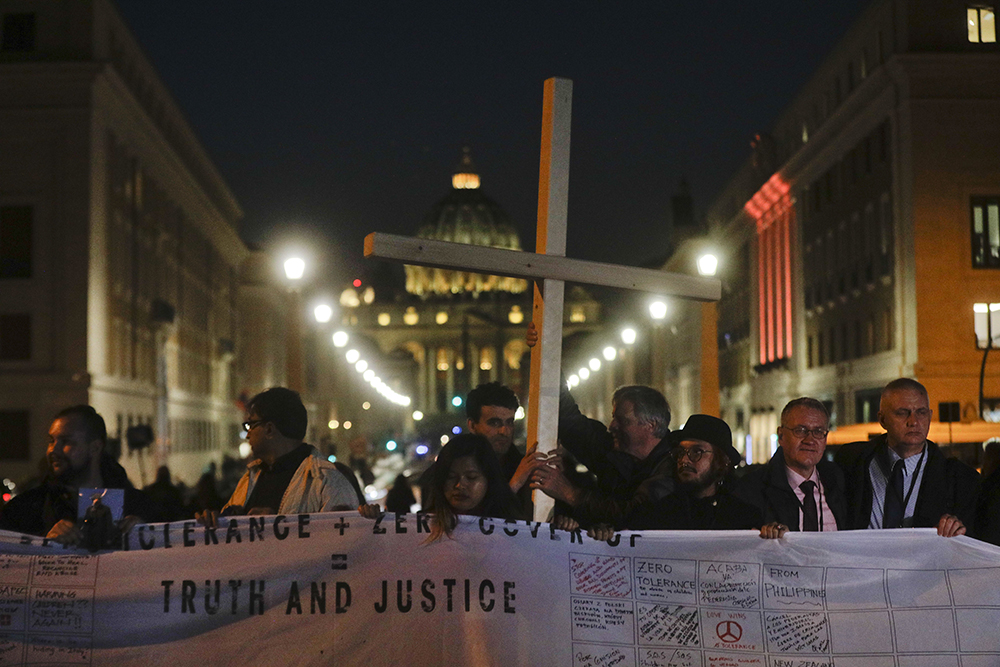 Survivors of sex abuse hold a cross as they gather in front of Via della Conciliazione, the road leading to St. Peter's Square, visible in background, during a twilight vigil prayer of the victims of sex abuse, in Rome Feb. 21, 2019. (AP/Gregorio Borgia, file)