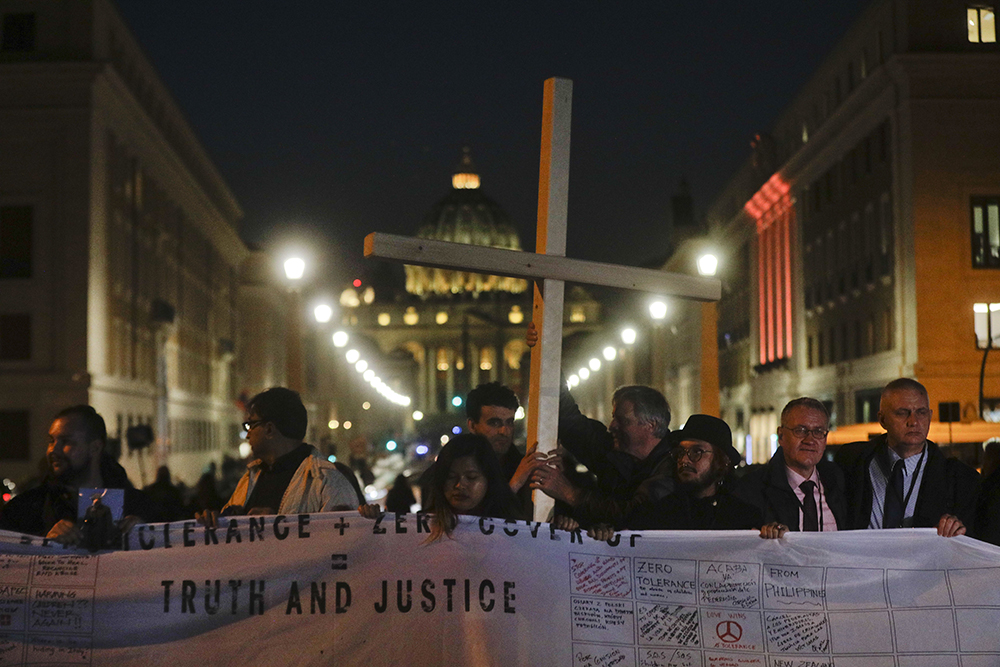 Survivors of sex abuse hold a cross as they gather in front of Via della Conciliazione, the road leading to St. Peter's Square, visible in background, during a twilight vigil prayer of the victims of sex abuse, in Rome Feb. 21, 2019. (AP/Gregorio Borgia, file)