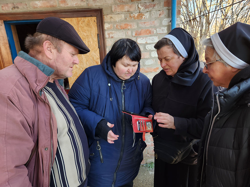 Inna Sirinok y su esposo Yurii, a la izquierda, en su casa destruida por los avatares de la guerra —ubicada en el pueblo ucraniano oriental de Preobrazhenkacon—, reciben la visita de las hermanas Lucia Murashko y Romana Hutnyk. (Foto: GSR /Chris Herlinger)