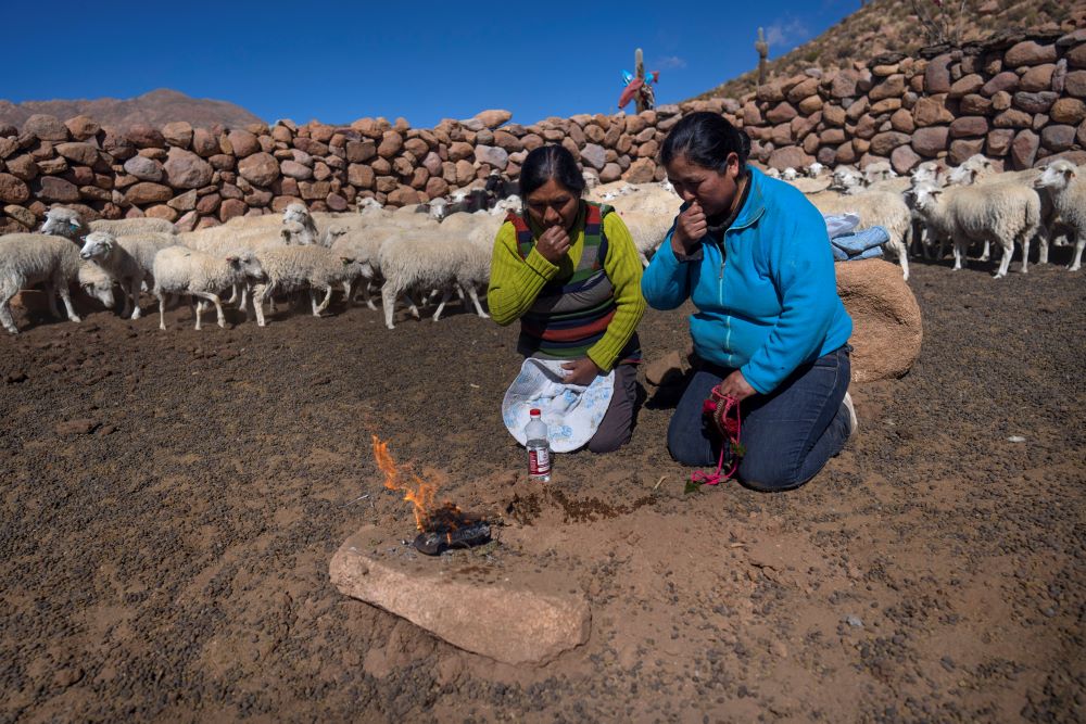 Vilma de Callata, left, and her sister, Katty de Callata, make an offering to the Earth while they look after their animals in Tusaquillas, Jujuy Province, Argentina, on April 23, 2023. 
