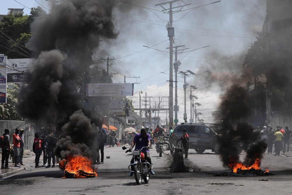 Haitian street violence Motorists pass a burning barricade in Port-au-Prince
