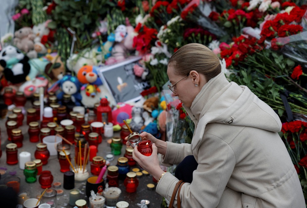 Crocus city concert hall attack Woman lights candle at makeshift memorial