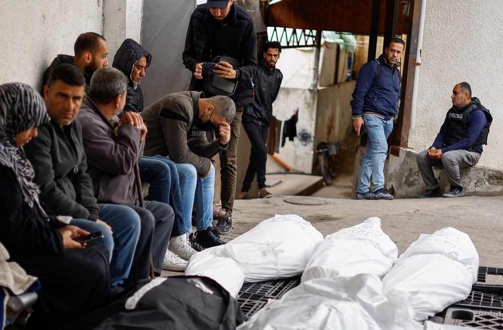Gaza strip casualties Palestinian mourn with shrouded bodies in foreground.