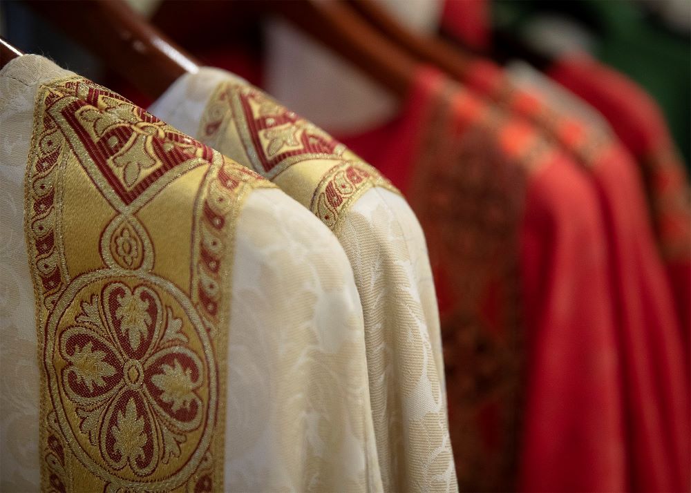 Clerical vestments hang on rack.