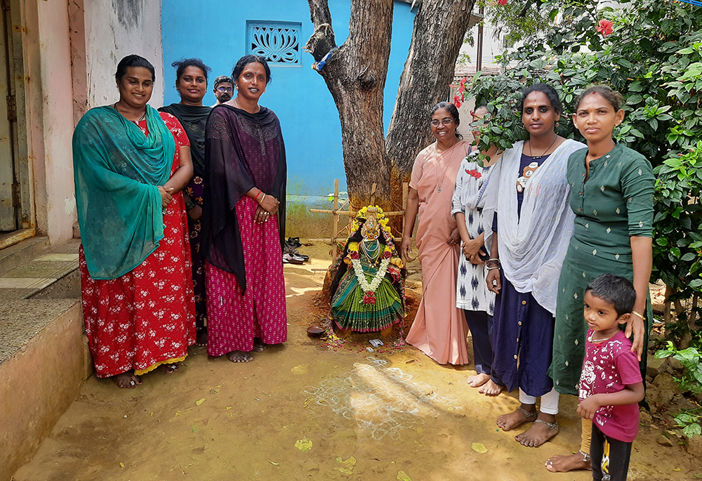 Srs. Stella Baltazar (fourth from right) and Anita Edwin (third from right hidden behind the leaves), members of the Franciscan Missionaries, stand near the deity of transgender women with Kovai Meera and her team at their residence in Coimbatore, a town in Tamil Nadu state southern India. The woman in green salwar suit with a child was visiting Meera. (Saji Thomas)