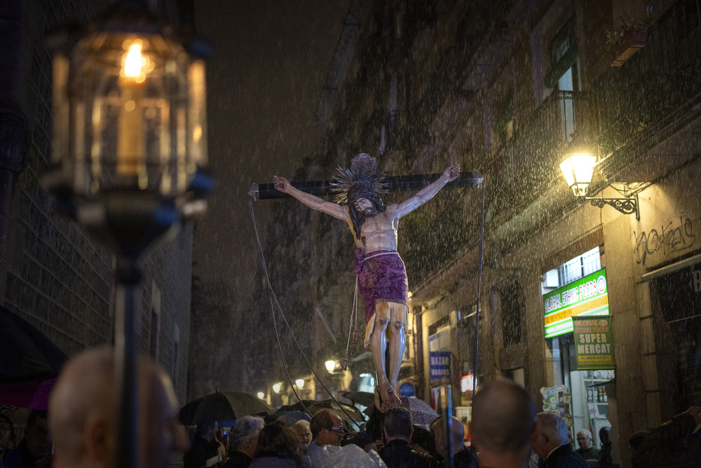 Large life-size crucifix depicting Holy Christ of the Blood carried at night through rain. 