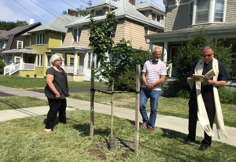 Fr. Frederick Daley, pastor of All Saints Church, blesses a tree planted by some of the members of the Caring For Our Common Home environmental task force in Syracuse, New York, in summer 2023. The task force just won the 2024 Cool Congregations Challenge in the "Community Inspiration" category. (Courtesy of Michael Songer)