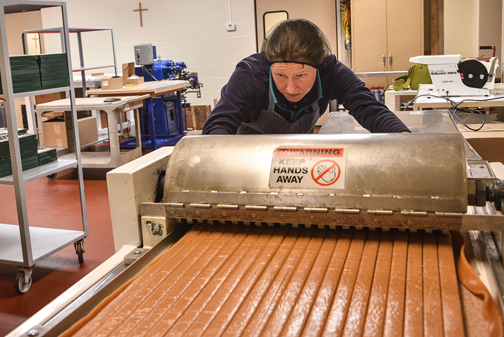 A Trappistine nun at Our Lady of the Mississippi Abbey near Dubuque, Iowa, operates a caramel cutting machine. (Courtesy of Bill Witt)