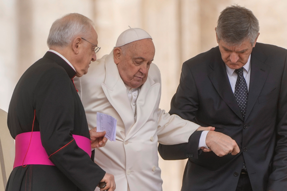 Pope Francis assisted while walking by prelate and aide