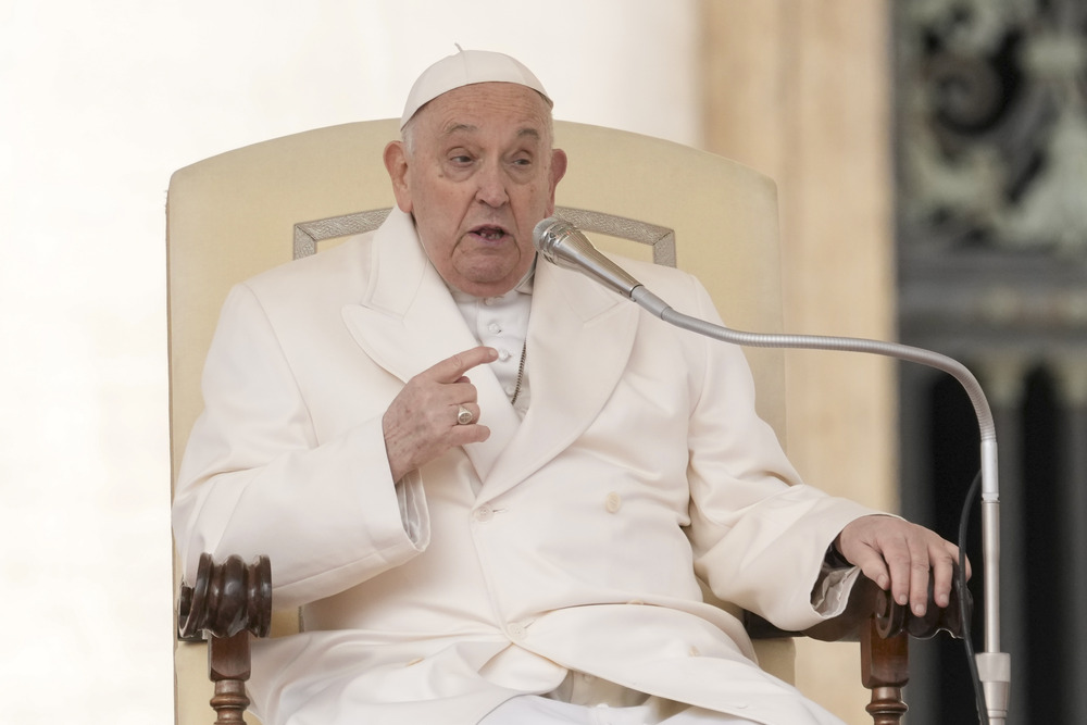 Pope Francis sits while delivering address at General Audience