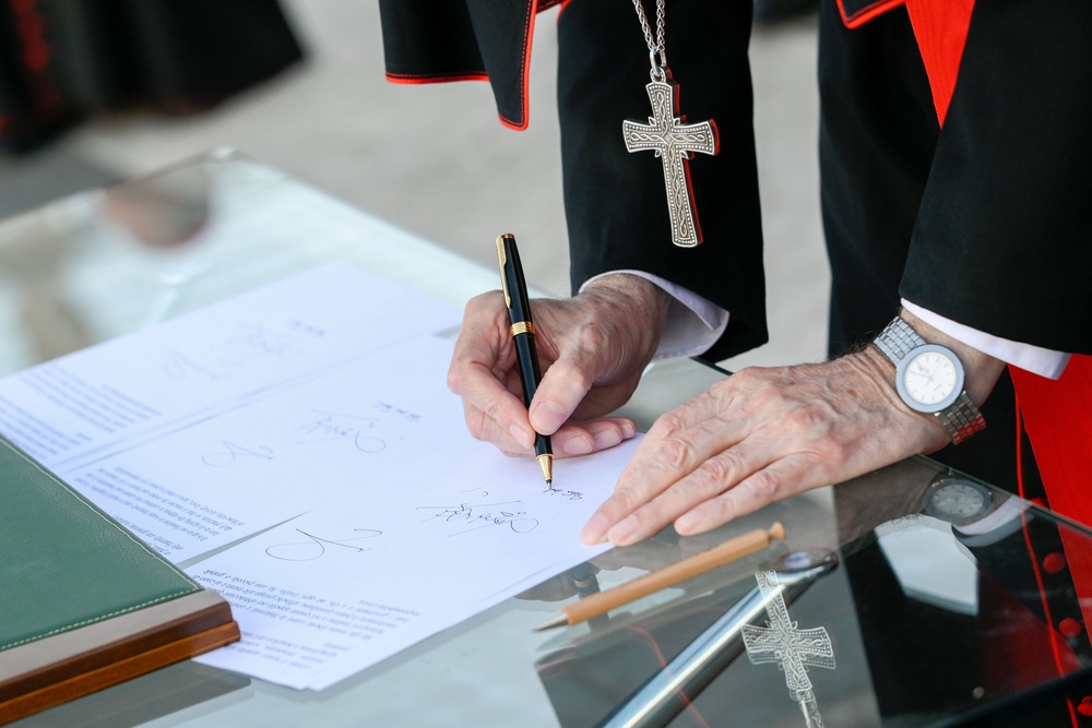 Cardinal Pietro Parolin signs Declaration on Human Fraternity Cardinals hands and pectoral cross visible