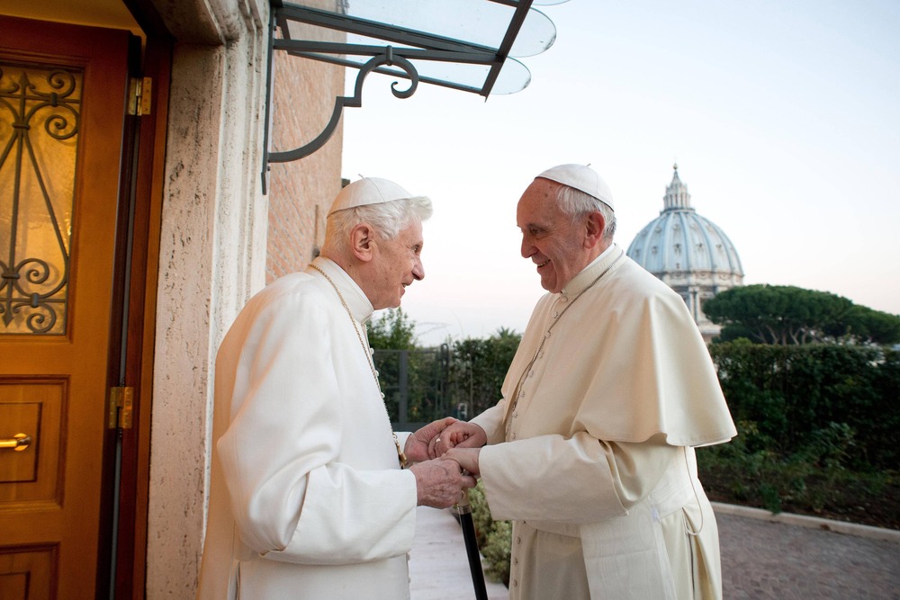 Pope Francis and Pope Emeritus Benedict XVI greet warmly.