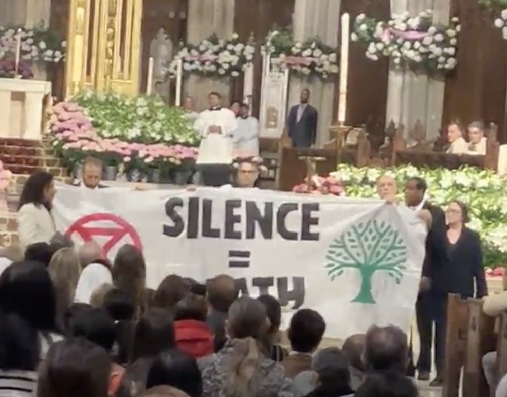 Protesters unfurl banner reading Silence = Death before altar. 