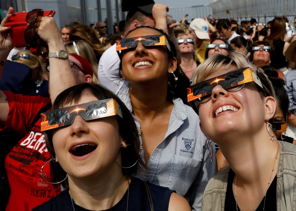 People wearing protective eyewear stare up at sky