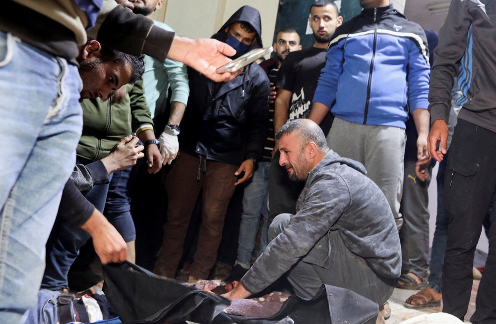 Man kneels, surrounded by people