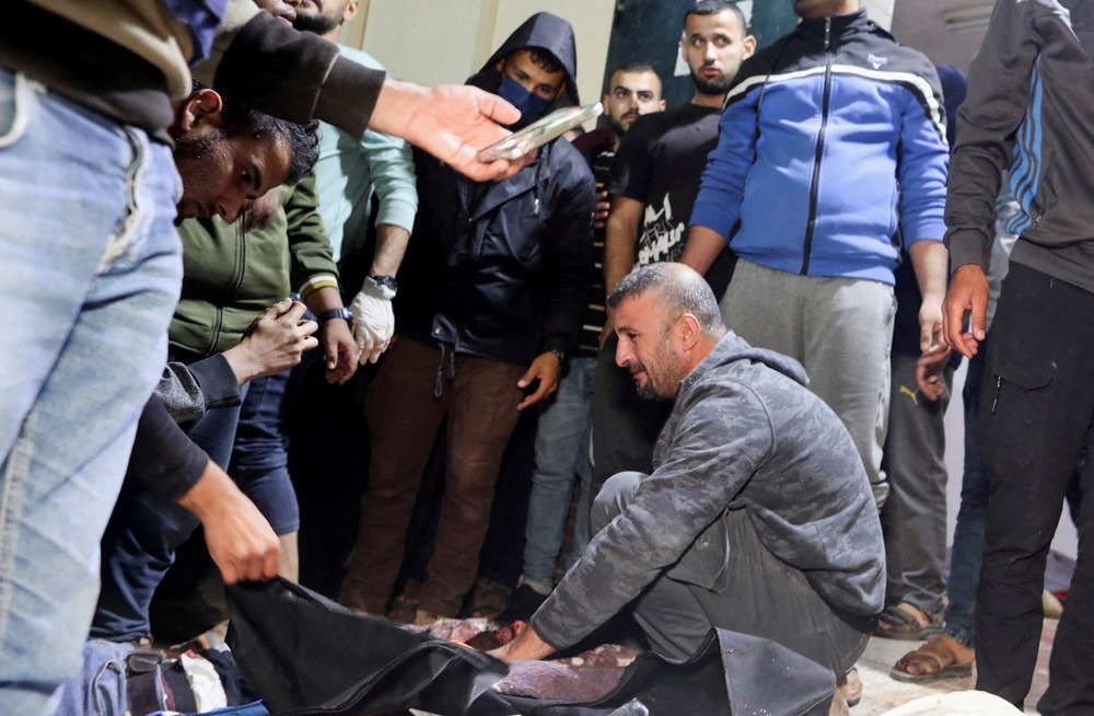 WCK killings, Gaza Man kneels, surrounded by people