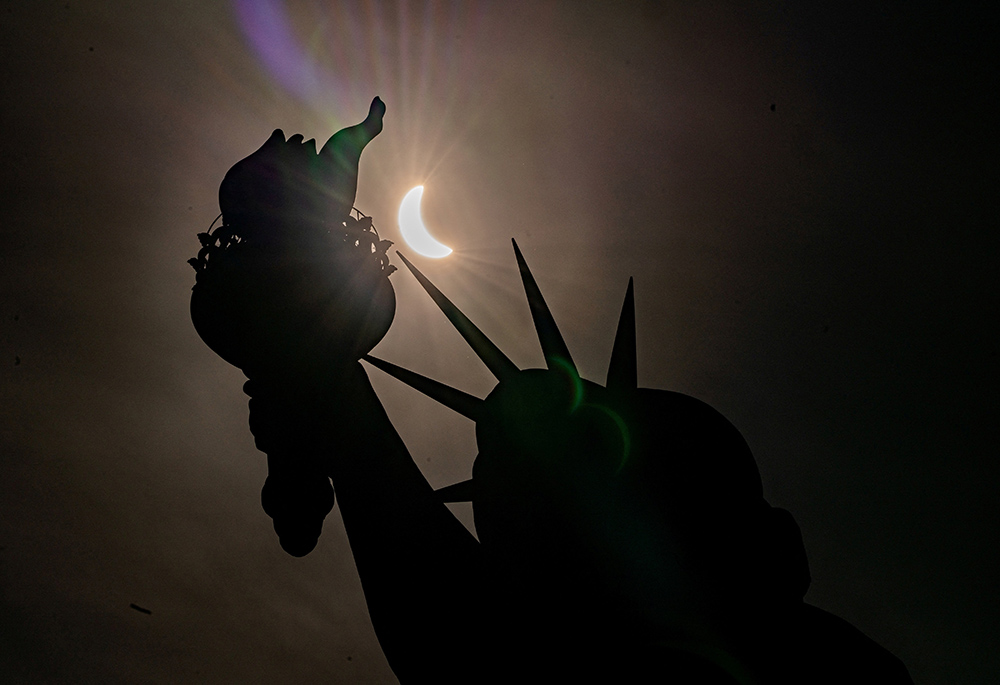 The Statue of Liberty is seen during a partial solar eclipse at Liberty Island April 8 in New York City. A partial eclipse was visible throughout all 48 contiguous U.S. states, while a total solar eclipse was visible along a narrow track stretching from Texas to Maine. (OSV News photo/Reuters/David Dee Delgado)