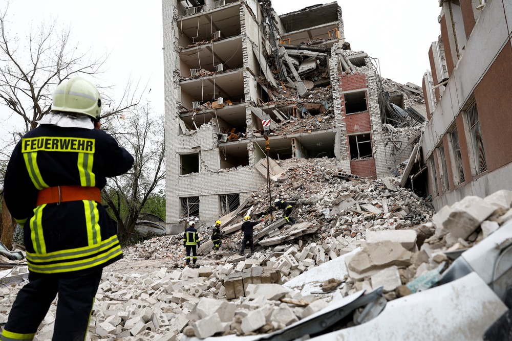 Ukrainian Catholic bishop calls Russian strike against civilians 'devastating' A first-responder, standing on rubble, faces a bombed-out building.