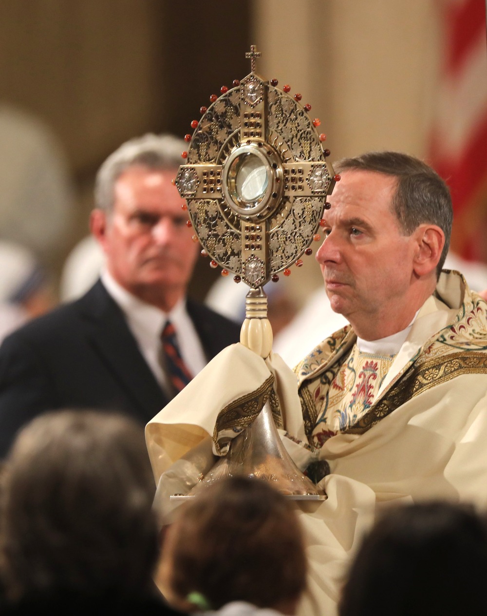 Bishop, vested, exposes Eucharistic Host in monstrance. 