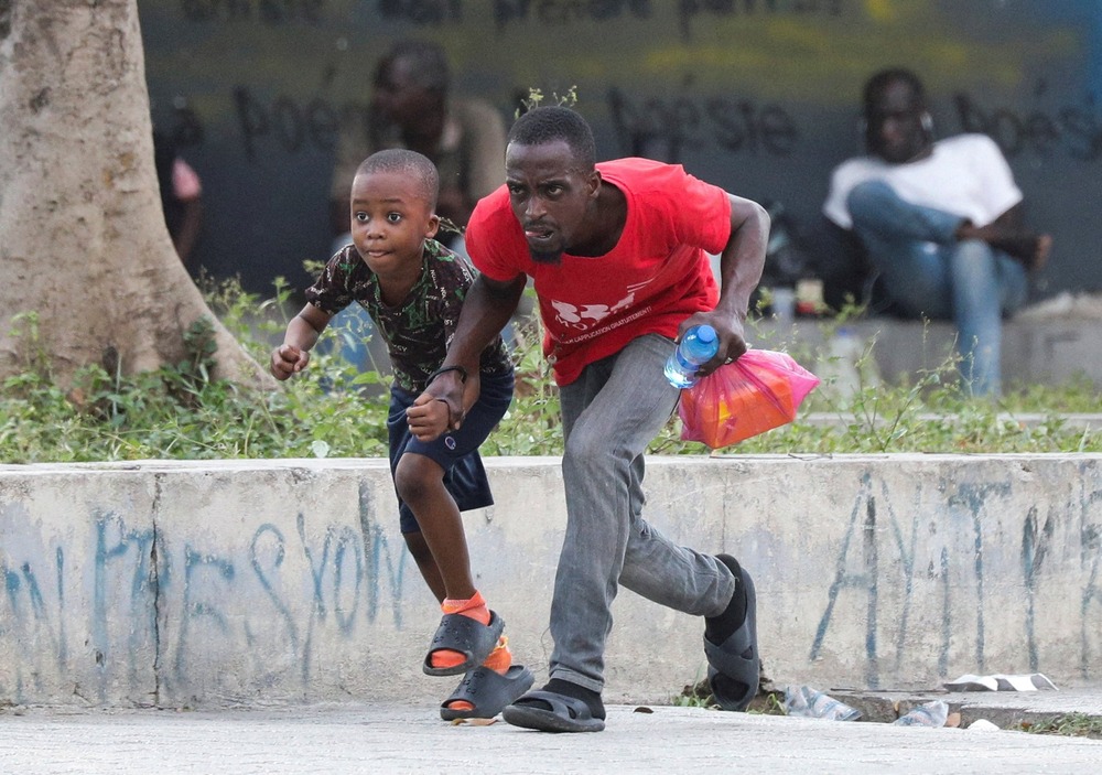 Archbishop Wenski of Miami condemns Haitian deportations A man and young boy duck and run through street.