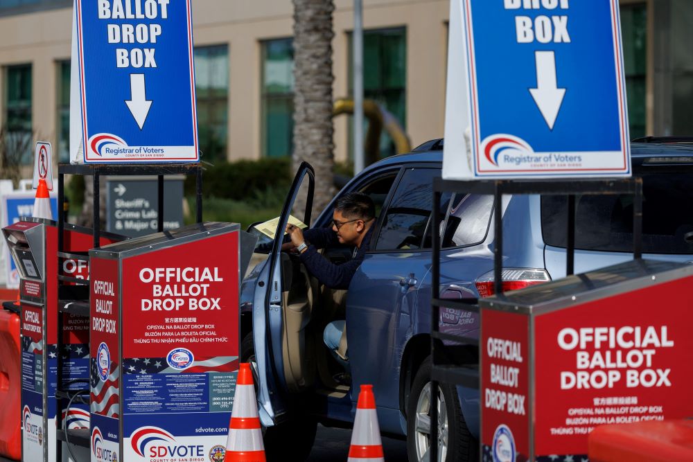 A voter drops a ballot paper into a drop box from his vehicle in San Diego during the Super Tuesday primary election March 5.