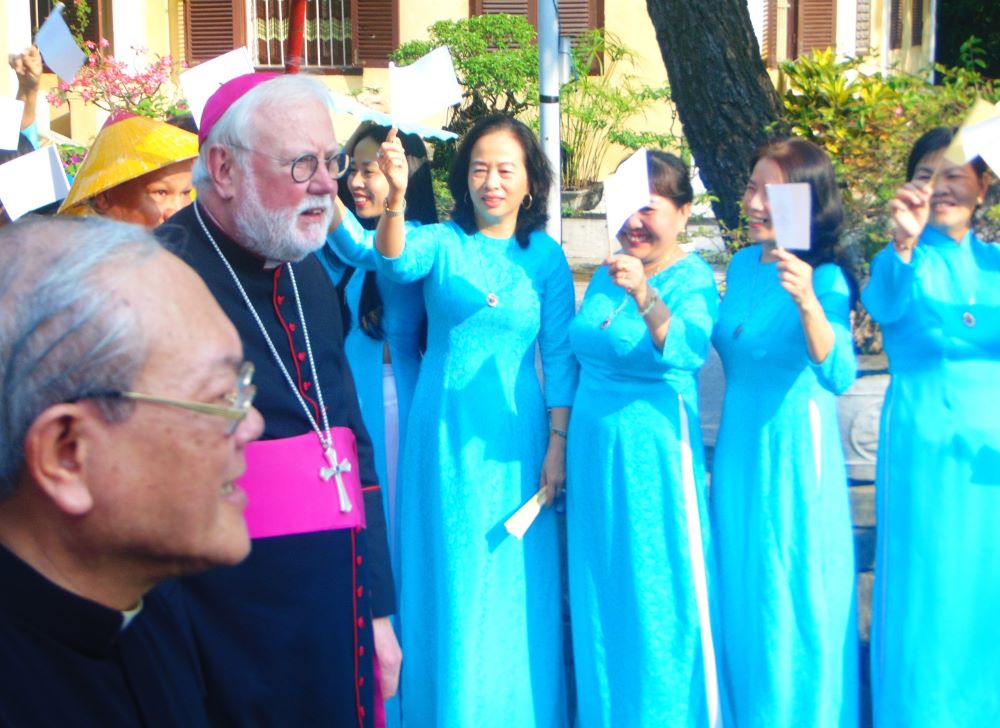 Archbishop Paul Gallagher is greeted by local women in traditional dress in Hue, Vietnam, on April 12. 