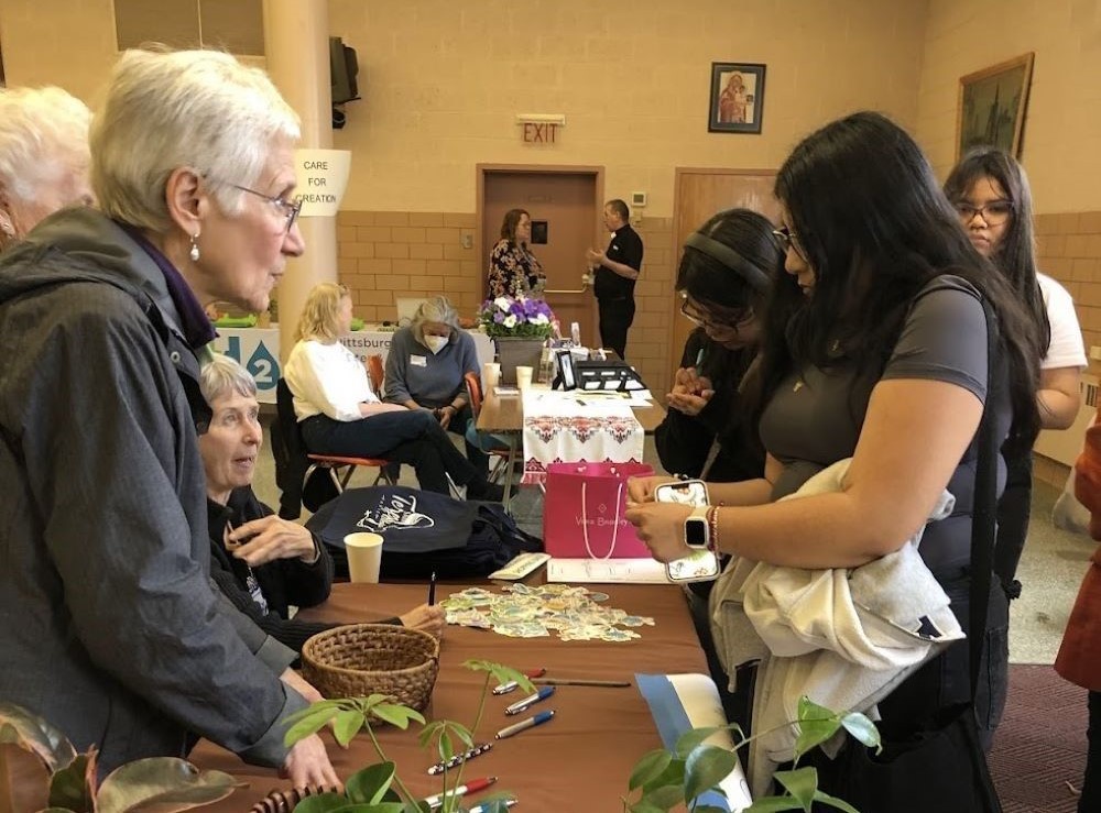 Roberta Zolkoski welcomes visitors to the Earth Day Community Resources Fair at St. Teresa of Kolkata parish, St. Catherine of Siena church, in Pittsburgh.