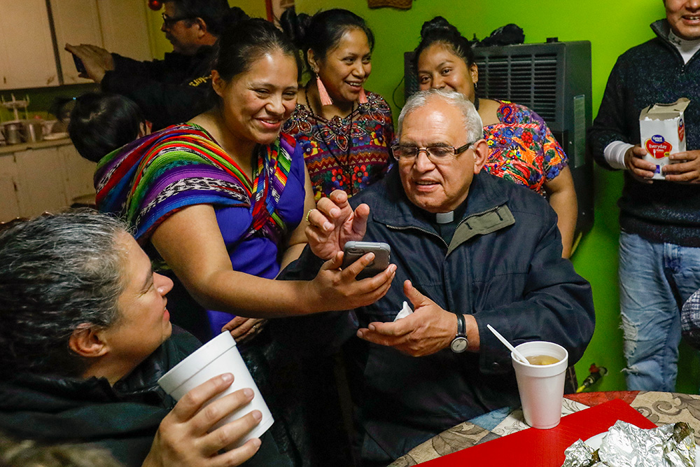 Cristel Cordona, second from left, shows photos of a recent marriage to visiting Guatemalan Cardinal Álvaro Ramazzini, at St. Anne Catholic Church in Carthage, Mississippi, Dec. 20, 2019. Ramazzini was at the parish to participate in a listening session with immigrants impacted by arrests by immigration agents at seven Mississippi food processing plants. (AP/Rogelio V. Solis, File)