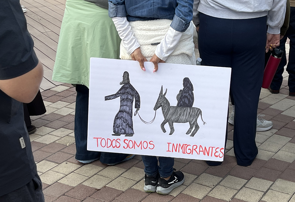 At San Jacinto Plaza in El Paso, Texas, a participant in the march and vigil holds a sign that reads, "We Are All Immigrants." (Evan Bednarz)