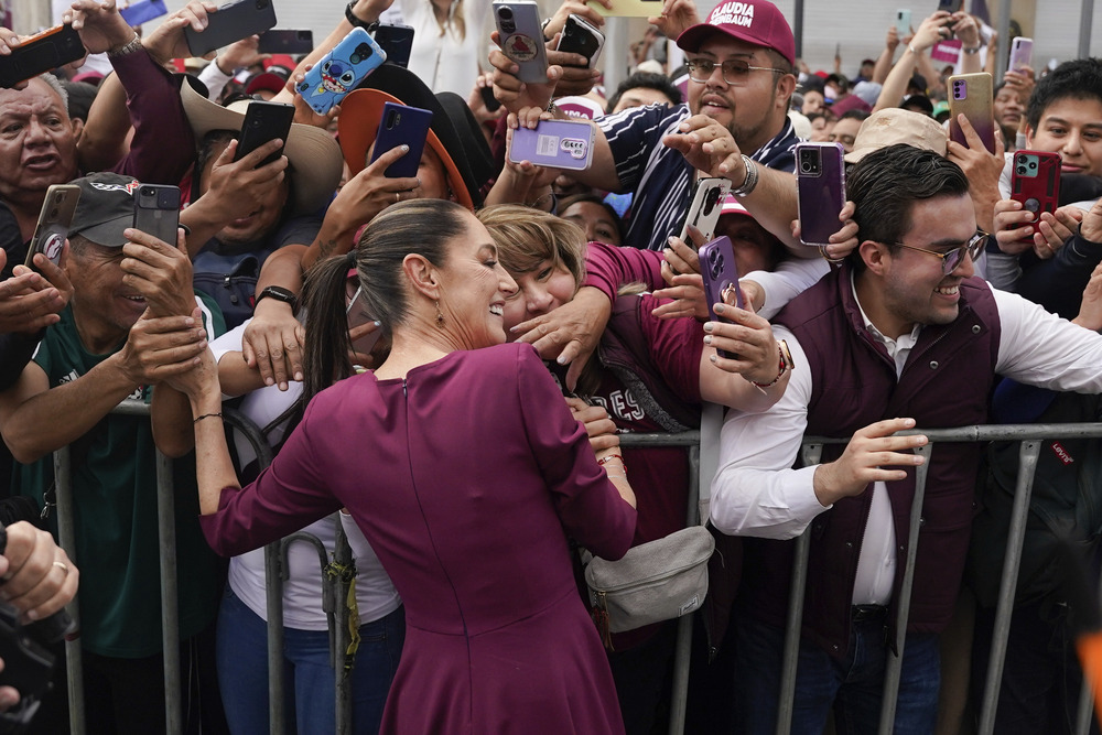 Mexico elections, Claudia Scheinbaum Scheinbaum leans over barrier to hug crowd member