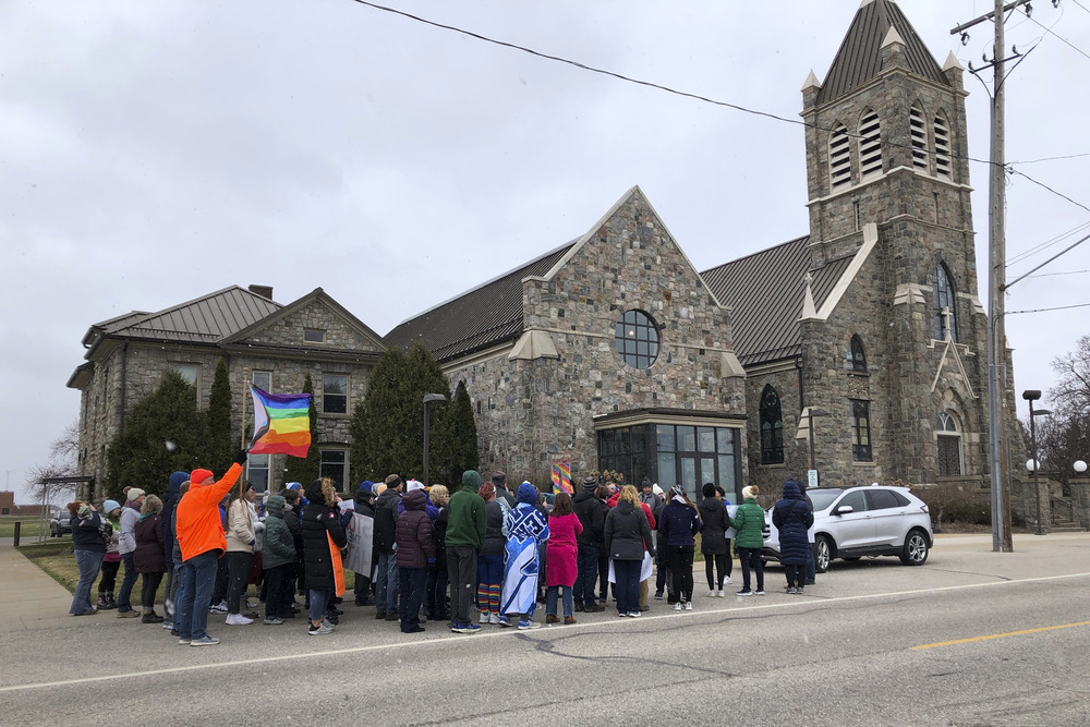 Catholic priest resigns from Michigan church following protests over his criticism of a gay author Protestors assemble outside stone church with pride flags