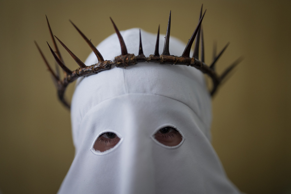 Spanish member of penitential order wears hooded regalia and crown of thorns.