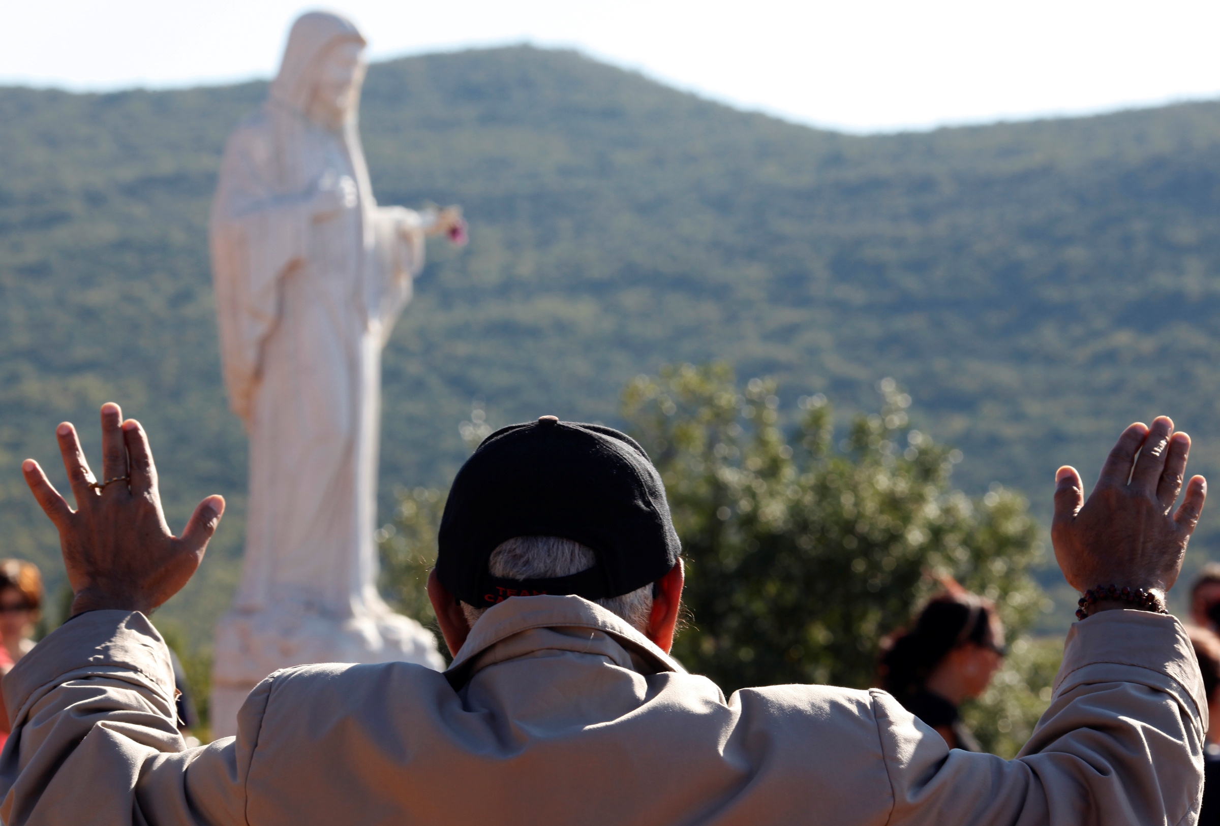 A man prays near a statue of Mary on Apparition Hill in Medjugorje, Bosnia-Herzegovina, in this Oct., 8, 2010, file photo. Pope Francis has decided to allow parishes and dioceses to organize official pilgrimages to Medjugorje; no decision has been made on the authenticity of the apparitions. (CNS photo/Matko Biljak, Reuters) 