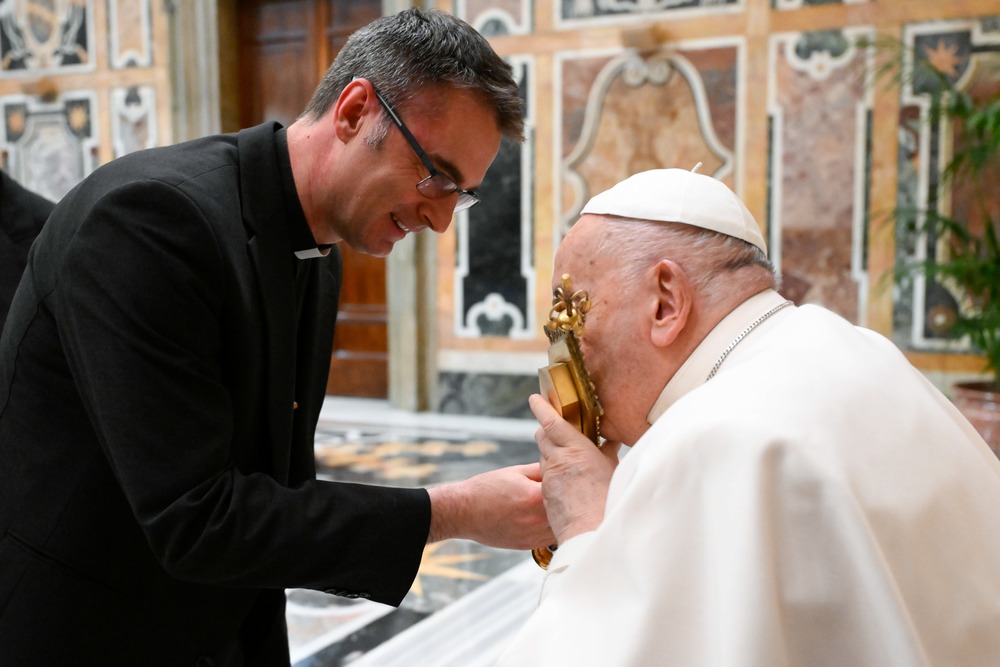 Pope Francis, reparation to the Sacred Heart, including abuse survivors Pope Francis kisses a gold reliquary while seated.
