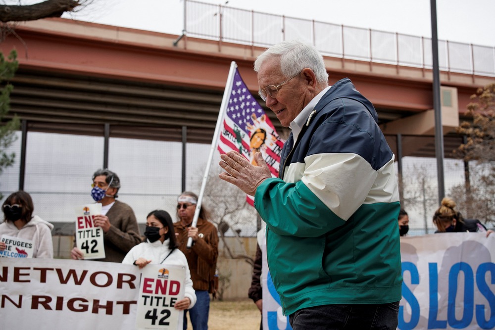 Texas Attorney General, Ken Paxton, revives attempt to shut down Annunciation House. Ruben Garcia prays at match with people in background.